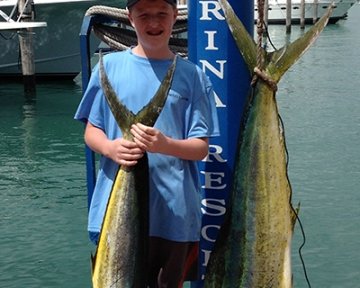 Kid posing with a couple of caught dolphin fish