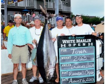 people posing with a tuna being weighed