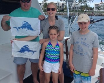Family holding up the blue marlin flag on deck