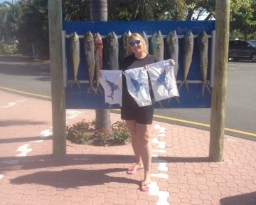Woman holding Blue marlin flag in front of the Sailfish marina sign